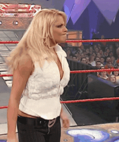 a woman is standing in a wrestling ring with a crowd behind her .
