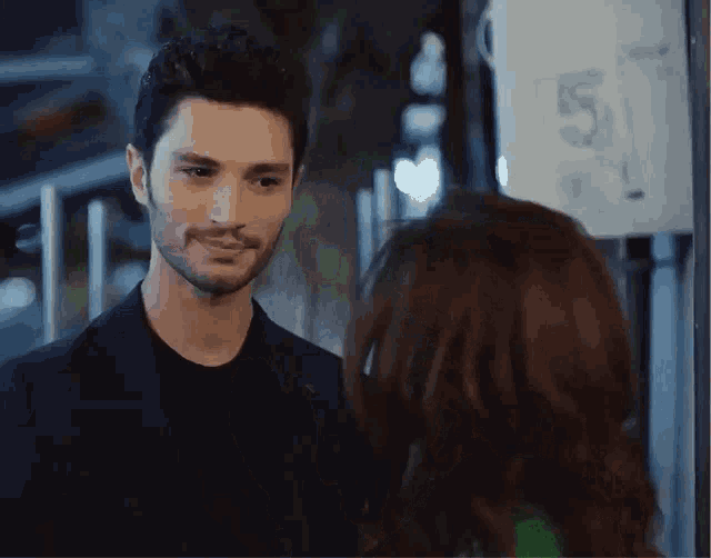 a man and a woman are looking at each other in front of a sign with the number 5 on it