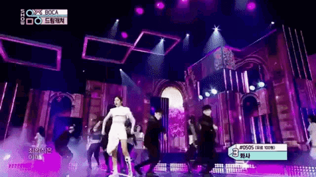 a woman in a white dress is dancing on a stage with purple lights and a sign that says boca