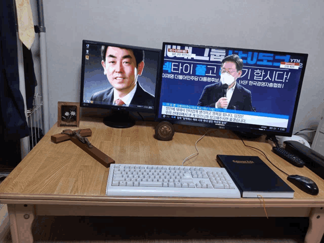 two monitors on a wooden desk with ytn written on one of them