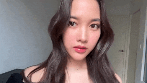 a close up of a woman 's face with long hair looking at the camera in a room .