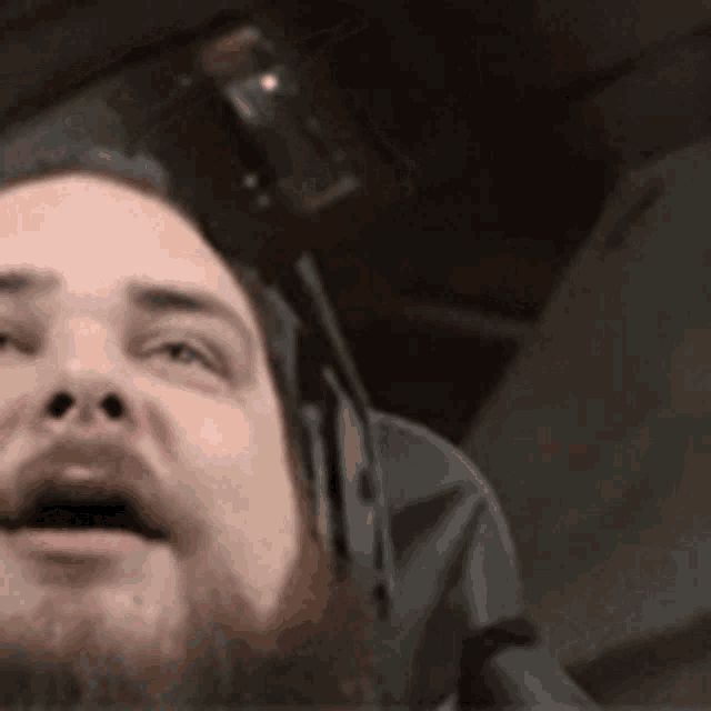 a man with a beard and headphones is making a funny face .