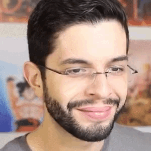 a man with a beard and glasses is smiling and looking at the camera .