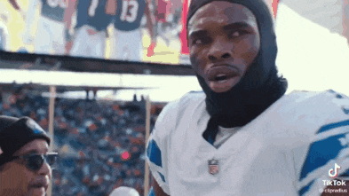 a football player wearing a mask is standing in front of a crowd at a stadium .