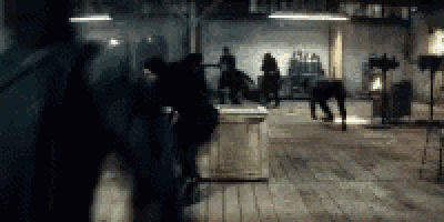 a group of people are standing in a dark room with a wooden floor .