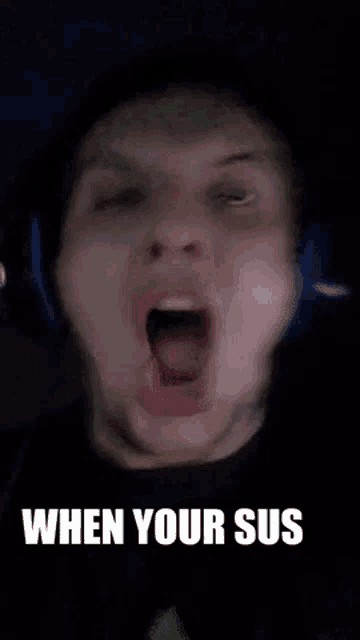 a man wearing headphones is making a funny face with his mouth open and the words `` when your sus '' below him .