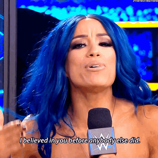 a woman with blue hair is talking into a microphone and saying i believed in you before anybody else did