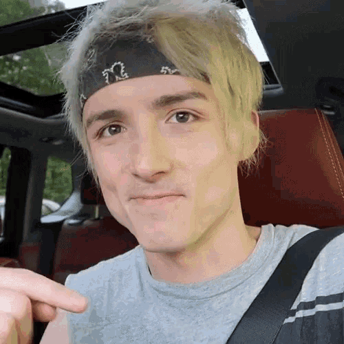a young man wearing a bandana is sitting in the back seat of a car .