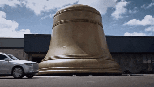 a large gold bell is sitting in front of a building