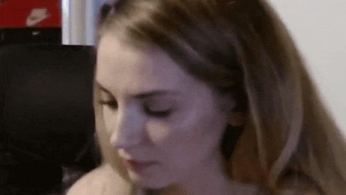 a close up of a woman 's face with her eyes closed and a blurred background .