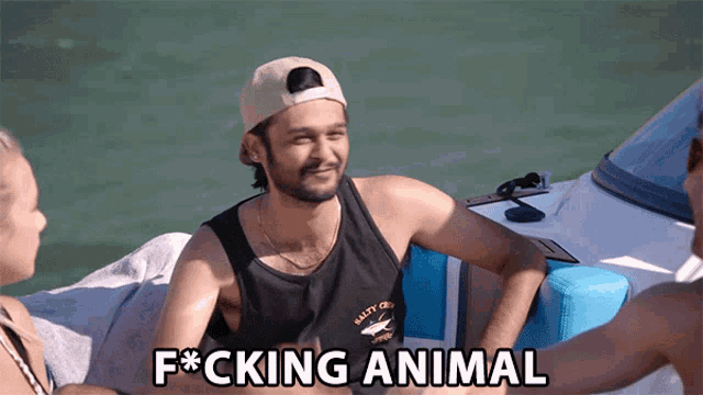 a man sitting on a boat with the words f * cking animal below him
