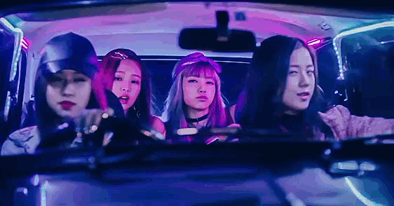 a group of girls are sitting in a car and looking out the window .