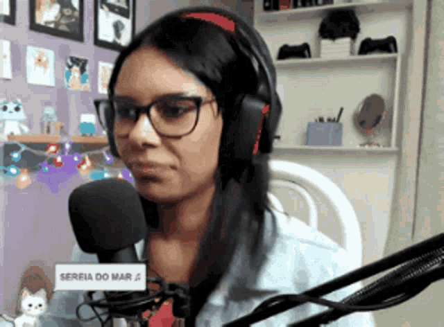 a woman wearing headphones and glasses is talking into a microphone that says " sereia do mar " on it