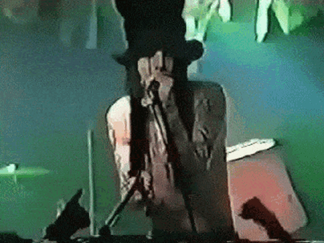 a man in a top hat is holding a microphone while standing on a stage .