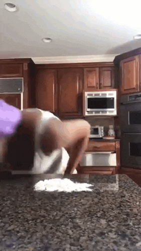 a woman is doing a handstand in a kitchen .