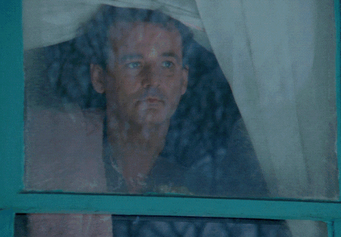 a man in a blue jacket is standing in front of a window with a towel on his back