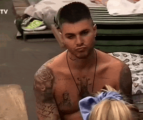 a shirtless man with a lot of tattoos on his chest is making a funny face .