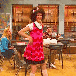 a woman in a pink dress is dancing in front of a group of people