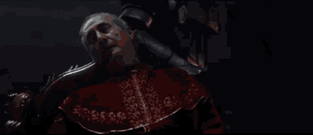 a close up of a person in armor holding a sword in a dark room .