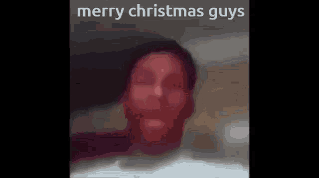 a blurry picture of a person 's face with the words `` merry christmas guys '' written on it .