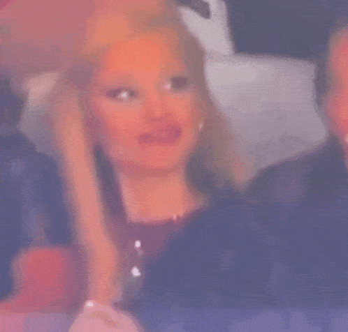 a woman with long blonde hair is sitting in a chair with a man .