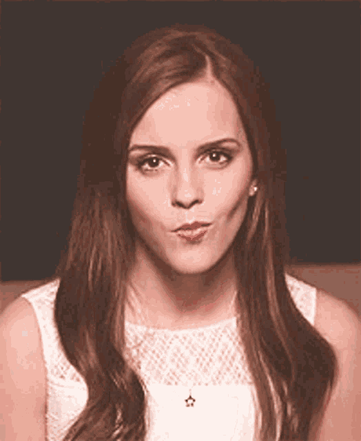 a woman with long brown hair is wearing a white dress and making a funny face
