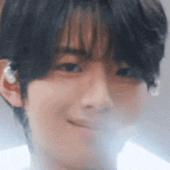 a close up of a person 's face with a blurred background and a smile .