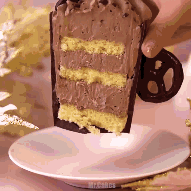 a person is holding a slice of cake on a saucer with mr.cakes written on the bottom