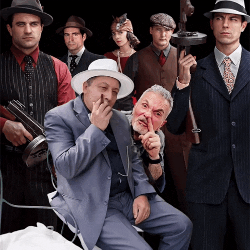 a group of men dressed in suits and hats pose for a photo
