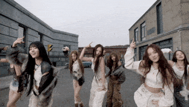 a group of women are dancing on a street in front of a building