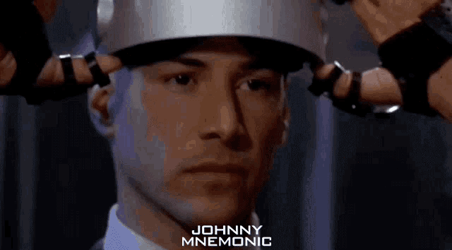 a close up of a man wearing a helmet with the name johnny mnemonic on the bottom right