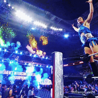 a woman in a blue outfit is jumping in the air in front of a sign that says world 's ntercontinental champions