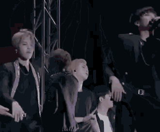 a group of men are standing on a stage holding microphones and dancing .