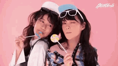 two young women are holding lollipops in their mouths .