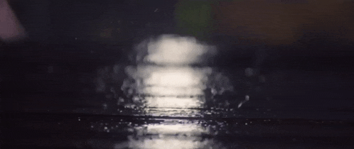 a close up of rain drops falling on a black surface
