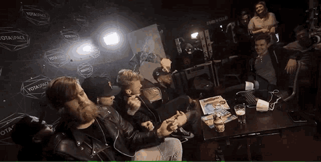 a group of men are sitting at a table in front of a sign that says notaspace