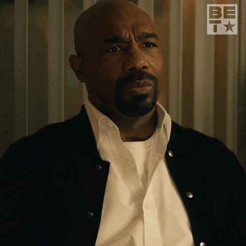 a man with a beard is wearing a black jacket and white shirt