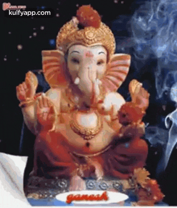 a statue of ganesha sitting on a table with smoke coming out of his mouth .