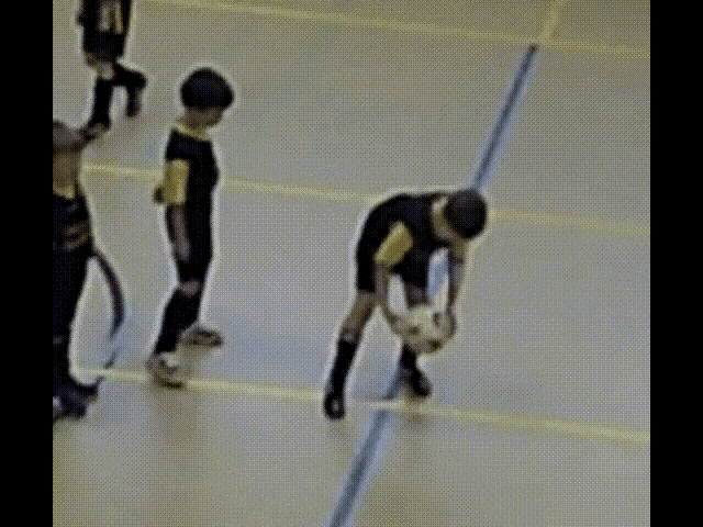 a soccer player is bending over to pick up his ball