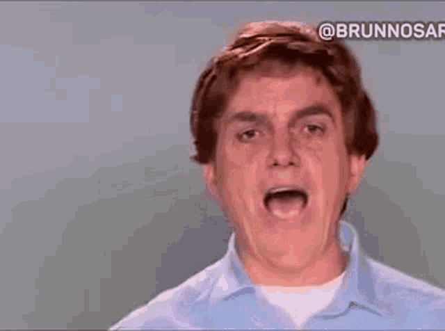 a man in a blue shirt is making a funny face with his tongue out .