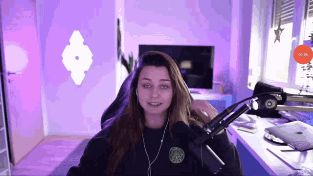 a woman sitting in front of a microphone with a purple background and a red button that says 00:00