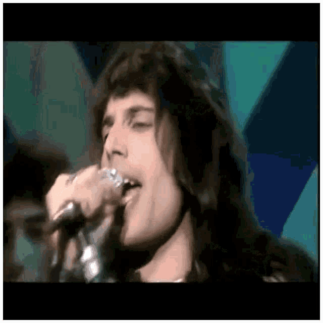 a close up of a man singing into a microphone on stage .