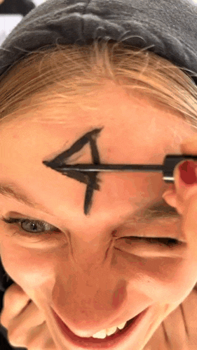 a woman has an arrow drawn on her forehead with black mascara