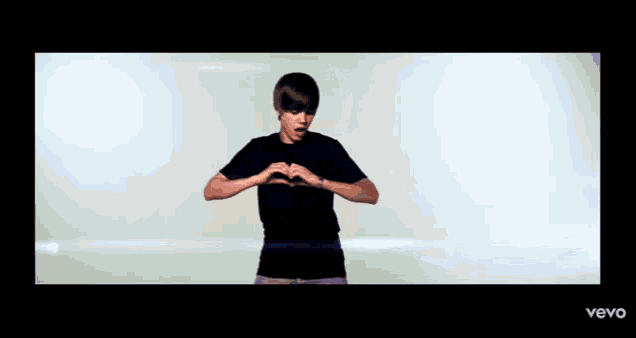 a boy making a heart shape with his hands in a vevo video