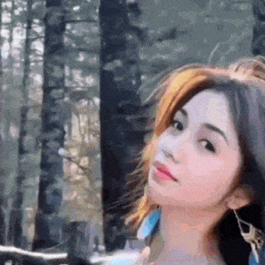 a close up of a woman 's face in front of a forest