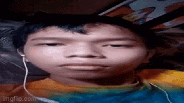 a young boy wearing headphones is making a funny face while laying on a bed .