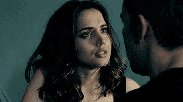 a man and a woman are looking at each other and the woman is making a sad face