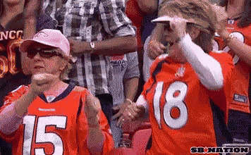 two women wearing denver broncos jerseys number 15 and 18