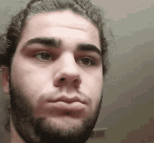 a man with a beard and a bun looks at the camera