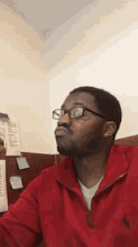 a man wearing glasses and a red sweater looks at the camera